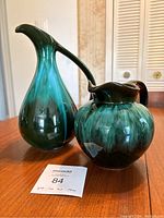 Two Blue Mountain Pottery pitchers, one large and one small, showing green to black glazing on wooden table