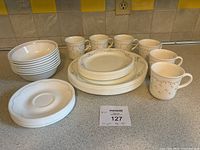 Photo showing all items: cups, bowls, side plates, dinner plates, and saucers arranged on countertop.