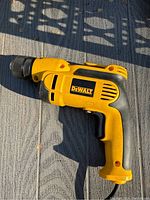 Side view of DeWalt yellow and black corded drill showing the DeWalt logo and handle grip.