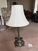 Full view of the 31-inch tall brass table lamp with white fabric shade on a carpeted floor.