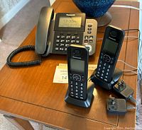 Panasonic corded phone on table with two cordless handsets and chargers