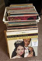 White plastic crate filled with vintage vinyl records, showing front and side rows with visible album sleeves including Strauss Waltzes by Andre Kostelanetz.
