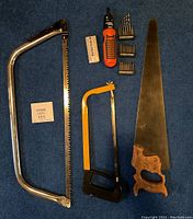 Top-down photo showing three saws: traditional hand saw, coping saw, and hacksaw, along with an electric screwdriver and drill bits.
