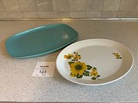 Two serving platters together on a kitchen counter. Turquoise melamine platter and ceramic floral platter shown side by side.
