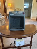 Titan brand space heater shown on small wooden table with single control knob and front heating element behind mesh.