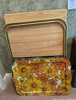 Stacked image showing two wooden trays and a floral yellow metal tray with tubular gold legs.