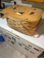 Photo of the wooden woven basket closed, showing the painted wooden lid with geese and handles.