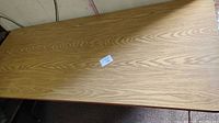 Top surface of the Samsonite banquet table showing wood grain finish and sticker with size info.