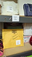 Shows part of shelving unit loaded with various boxes and items, including a yellow envelope marked 'Caution Fragile' and various packaging items.