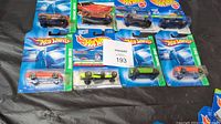 Top view of all 8 Hot Wheels Treasure Hunts cars arranged in a row still in packaging.