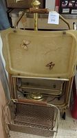 TV trays with butterfly and leaf designs stacked above floor lamp base and metal magazine rack, showing some wear and construction details.
