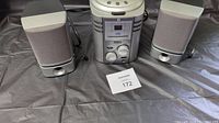 Photo showing central audio unit and two matching speakers on a black surface with lot tag number 172.