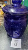 Side view of jar showing embossed text 'PEANUTS' in cobalt blue glass, with some surface dust and grime.