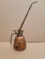 Front angled view of the vintage metal oil can showing the body, handle and long curved spout