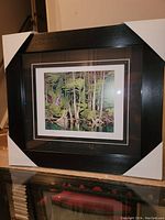 Framed fine art print of a blue heron in a forest setting, professionally framed with corner protectors on a reflective surface.