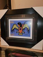 Front angled photo of framed David Morrisseau print "Thunderbird Man Warrior" with corner protectors on frame.
