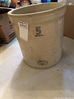 Side view showing '5 Imperial' marking and Medalta Potteries Ltd. logo on beige crock with some surface marks.