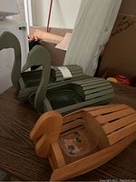 Three bird-shaped wooden planters, two painted grey and one natural wood, displayed on a wooden surface.