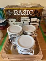 Three white ceramic canisters in a wooden tray with airtight clamp lids and knob handles.