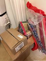 View of stacked cardboard boxes and rolled Christmas wrapping paper in red and multicolor patterns.