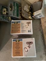 Two boxed Defiant Halogen Spot Light ceiling mount fixtures with chrome finish, and various boxes and loose interior and entrance door handles, including glass knob styles and lever handles.