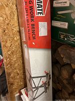 Jobmate folding work bench box standing upright against wall with printed product image and specifications visible.