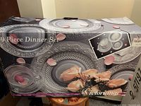Box showing unopened 20 piece Victoriana glass dinner set with decorative plates featuring floral embossed patterns.