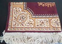 Folded corner detail showing silk effect surface, decorative gold and cream floral pattern and 2 inch cream fringe.