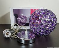 Photo showing the amethyst purple spherical lamp shade with circular silver metal ring accents, the silver ceiling mount, wiring, and bulb socket.