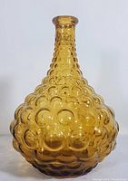 Full view of the amber bubble glass bottle showing bulbous base and tapered neck.
