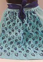 Front view of vintage apron showing floral panel and purple tie.