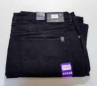 Folded black denim jeans showing front pocket and tags indicating size 40x32 and brand.