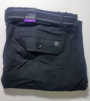 Folded black men's cargo shorts with a belt, size and brand tags visible