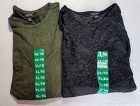 Two folded long sleeve tops side by side, olive green and charcoal grey, each with XL size sticker on front.