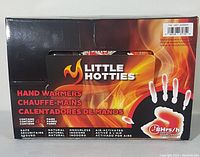 Front view of Little Hotties hand warmers sealed box displaying flaming hand graphic and product benefits in three languages.
