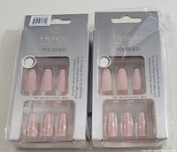Two unopened Helios Polished Nail Systems sets showing 24 soft pink polished faux nails each, visible through clear packaging front.