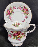 Front angled view of teacup with floral pattern and saucer behind showing matching floral decorations and gold trim.