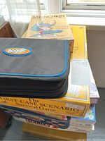 Stack of several board games including a Boggle zippered game case on top, then The Worst-Case Scenario Survival Game, and Munchkin visible among others.