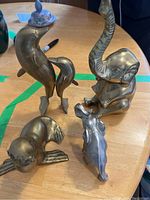 Four animal figurines on a wooden surface including elephants, a sea lion and dolphins
