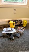 Overview of Curtis radio/CD player, yellow VHS rewinder in box, two black flashlights, and other items on carpet