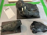 Overhead view of three walrus figurines on a table, showing details of the carvings and base materials