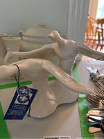 Side view of the white ceramic flying geese sculpture with Blue Mountain Pottery tag visible