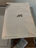 User manual with JVC logo and text, showing wear and damage on edges