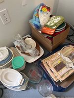 Box with assorted plates, bowls, oven mitts, and kitchenware items shown from above and side