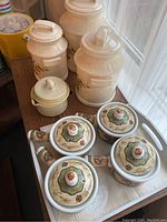 Full set including 4 onion soup bowls with lids, white tray, and 4 canisters (3 large, 1 smaller) all arranged on a wooden surface near window.