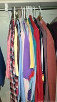Closet photo showing assorted women's tops on hangers with colors including pink, yellow, purple, blue, red, cream, and brown.