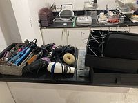 Photo showing blow dryers, curling irons, hair straighteners on a surface alongside organizers and a box with costume jewelry