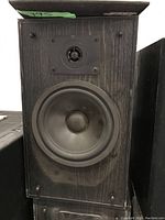 Pair of Bose speakers, showing front of one speaker with woofer and tweeter, wood grain backing, and four mounting screws.