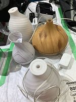 Four scent diffusers of various styles and a Sylvania clock, arranged on a surface with their cords and plugs visible.