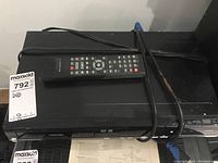 Front view of Toshiba DVD video recorder with tied power cable and remote control placed on top.